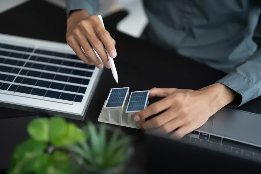 Designer examining miniature solar panels beside laptop
